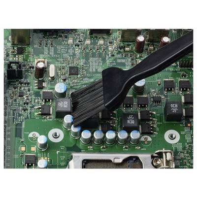 Gros plan d'une carte de circuit étant nettoyée avec un pinceau, balayant les composants électroniques et les condensateurs.
