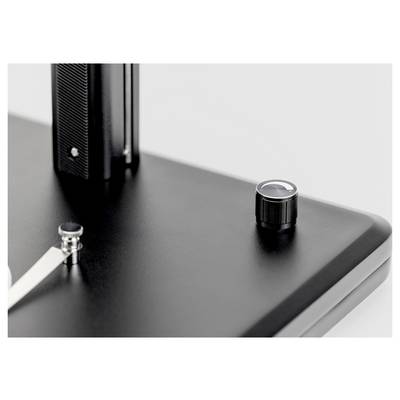 Un gros plan d'une surface métallique noire élégante avec un bouton brillant et un petit support, mettant en évidence des éléments de design industriel moderne.
