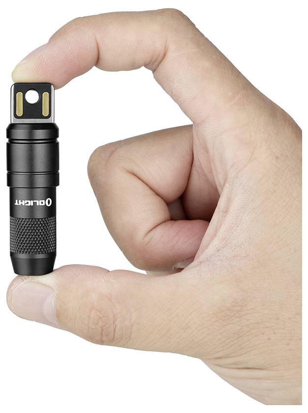 Une main tient une petite lampe de poche noire avec 'OLIGHT' écrit dessus, mettant en évidence sa taille compacte.