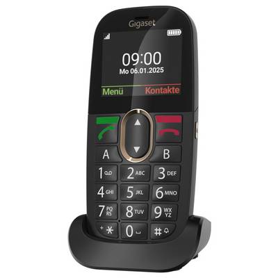 Un téléphone mobile noir avec de grands boutons dans un berceau de charge. L'écran affiche « 09:00 Lu 06.01.2025 » avec les options « Menu » et « Contacts ».