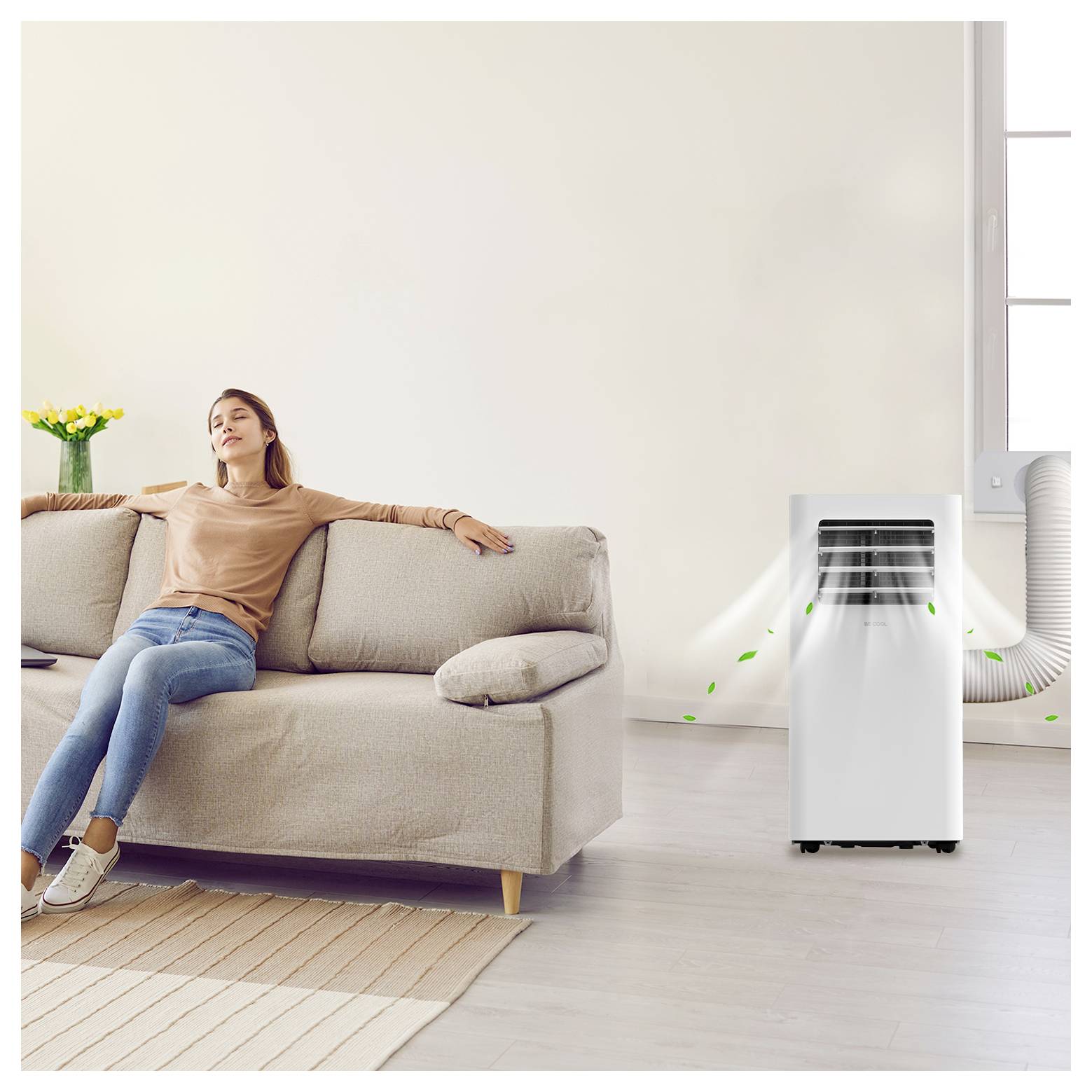 Une femme se détend sur un canapé dans une pièce lumineuse avec un climatiseur portable en fonctionnement à proximité, indiqué par des lignes de circulation d'air.