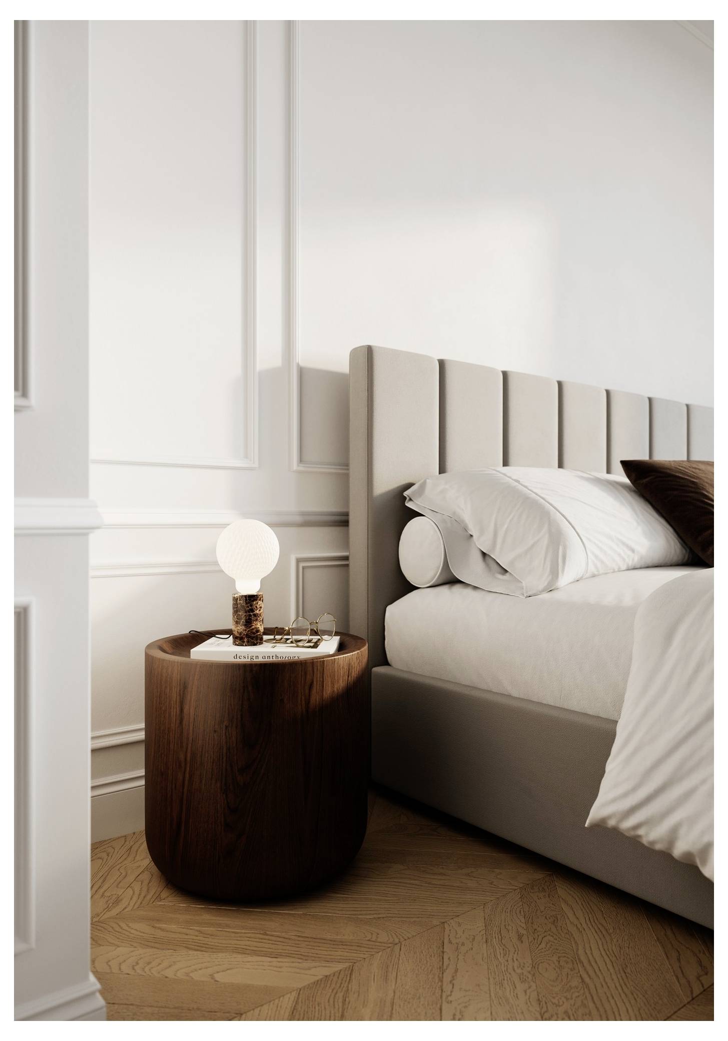 Une chambre à coucher moderne avec un lit rembourré beige, une literie blanche et une table de nuit ronde en bois sur laquelle reposent une lampe et de petits objets.