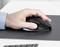 Une main manœuvrant une souris d'ordinateur ergonomique noire sur une surface sombre, indiquant un usage professionnel d'ordinateur ou du travail de bureau.