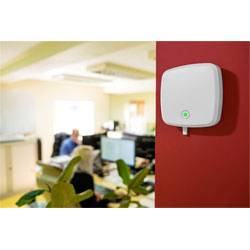 Un appareil sans fil montré au mur avec un indicateur vert lumineux, situé dans un bureau, assurant la connectivité pour les employés à leurs bureaux.