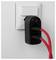 Un adaptateur d'alimentation noir branché dans une prise murale blanche, avec deux câbles rouges connectés, suggérant une configuration de charge ou électrique.
