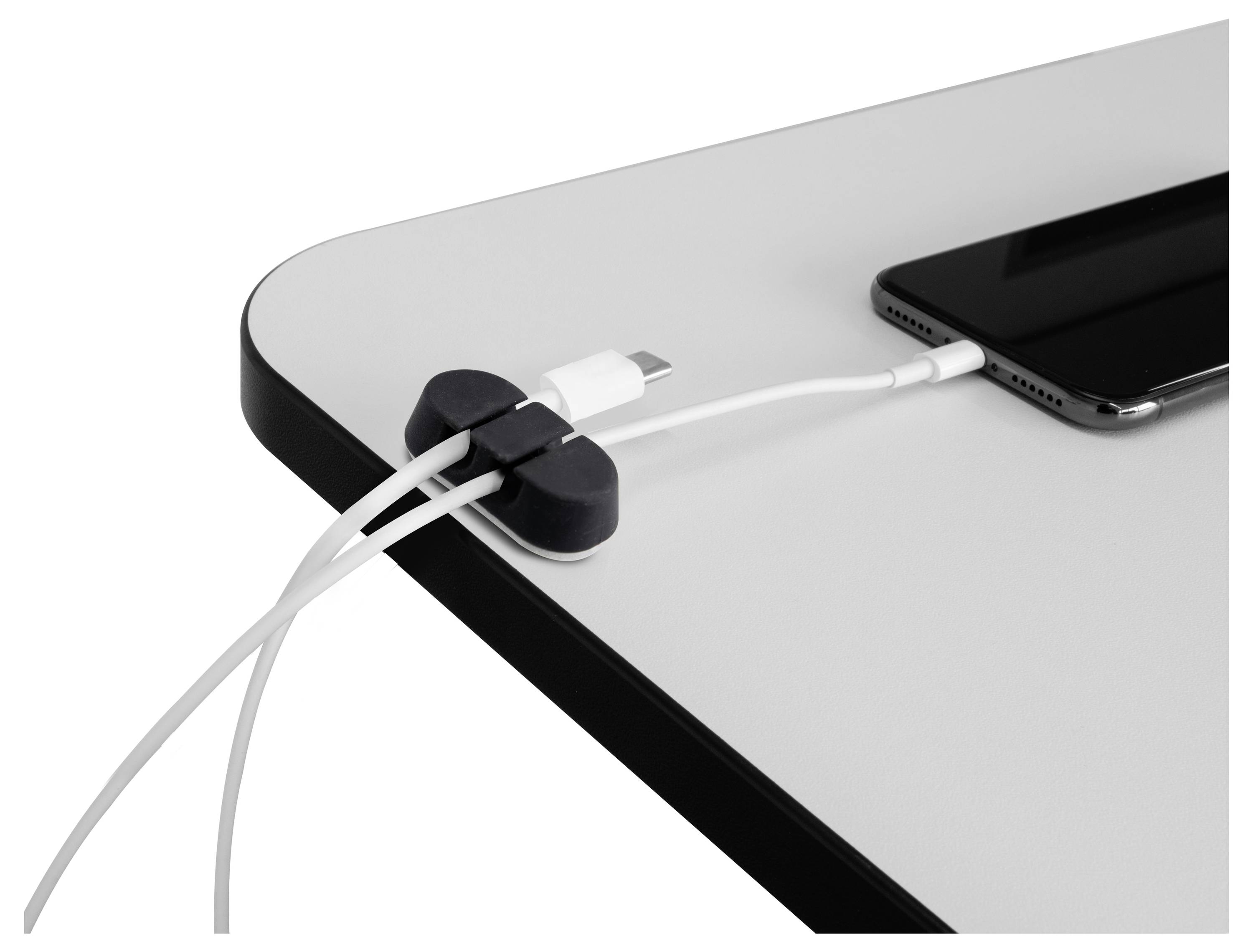 Un smartphone connecté à un câble de chargement sur une table avec des supports de câbles organisant proprement plusieurs cordons sur le bord.