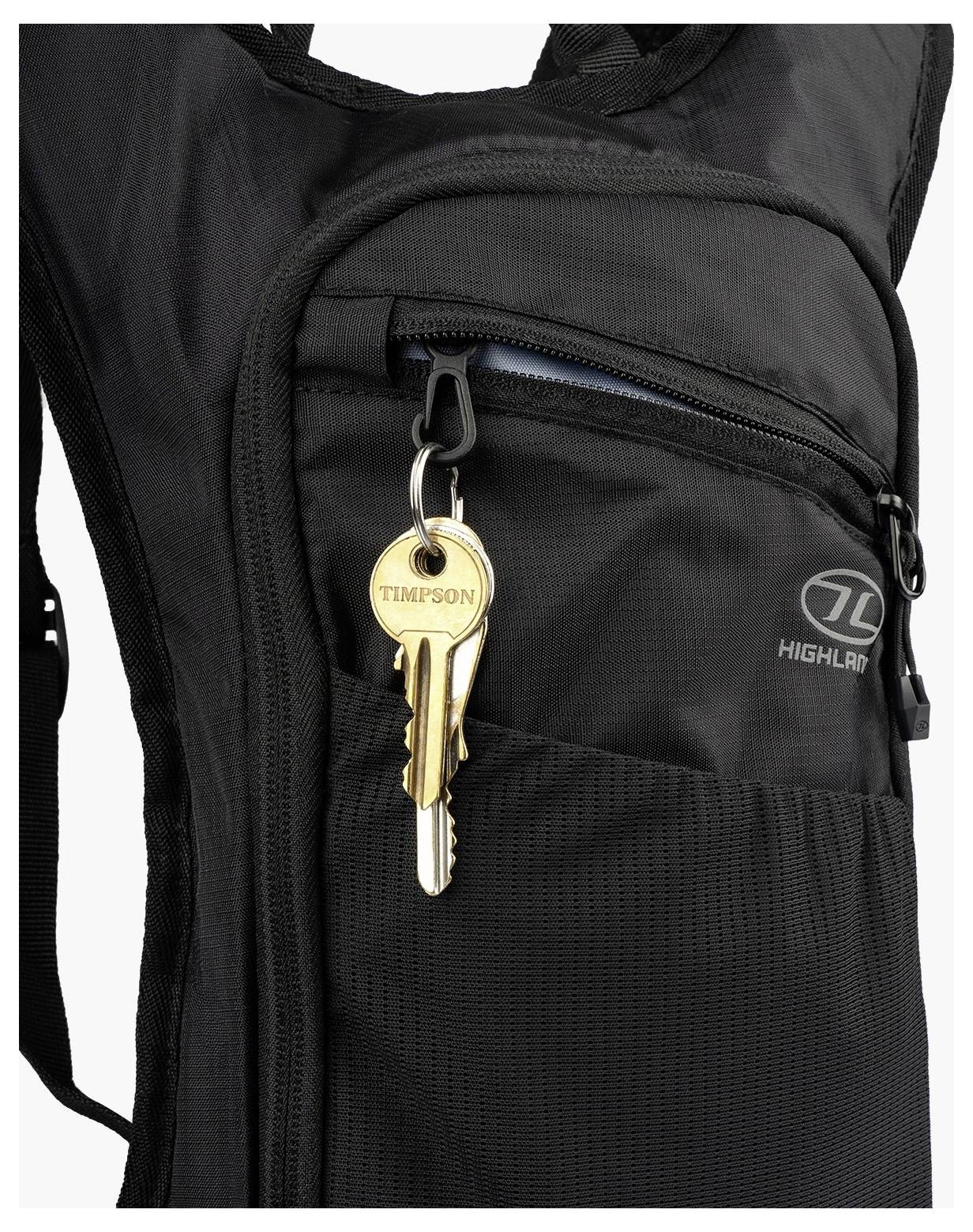 Un sac à dos noir avec le logo 'Highlander' visible présente une poche avant avec fermeture éclair contenant un porte-clés avec deux clés attachées.