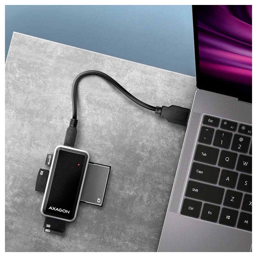 Adaptateur multiport USB-C connecté à un ordinateur portable, avec des emplacements pour cartes mémoire et des ports visibles sur un bureau.