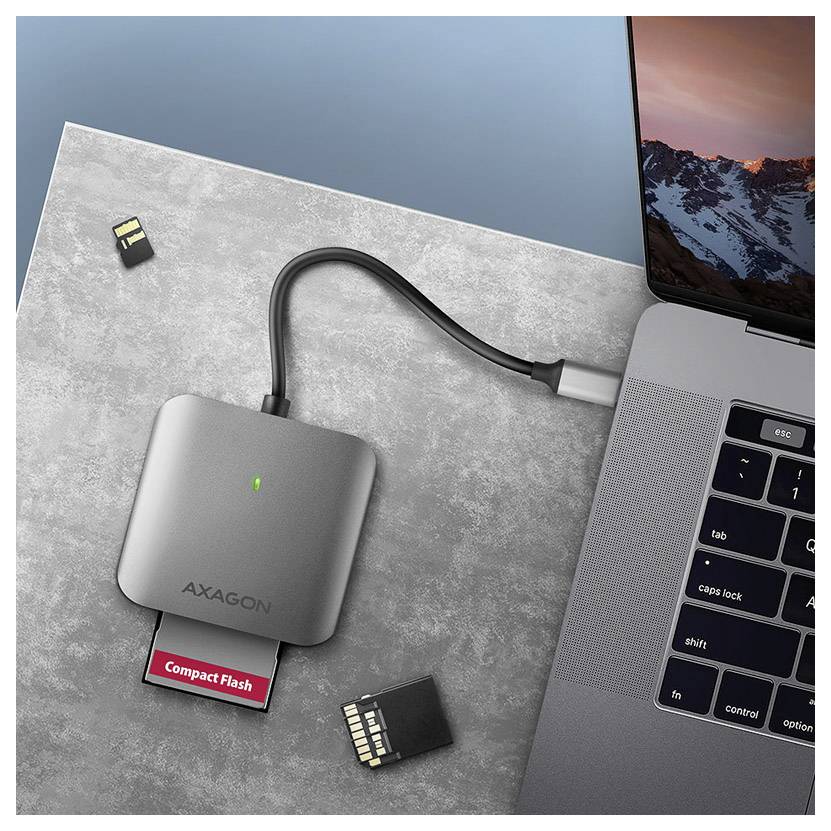Lecteur de carte CompactFlash Axagon compact connecté à un ordinateur portable avec une carte CompactFlash insérée et deux cartes mémoire à proximité.