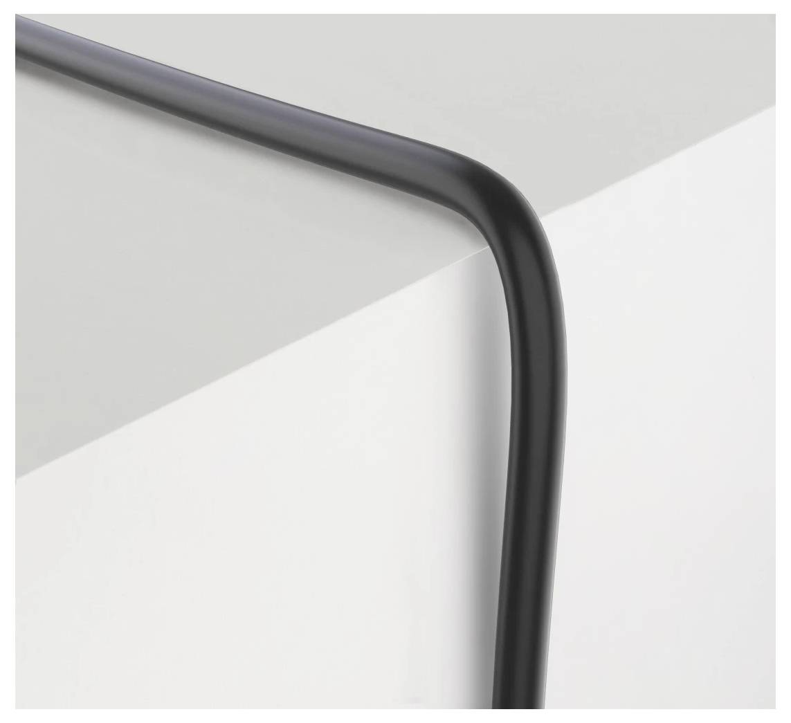 Un objet noir unique, allongé, forme un coin doux sur une surface blanche et grise lisse, créant une apparence minimaliste et élégante.