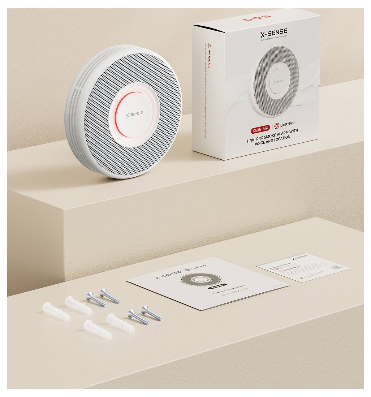 Une alarme incendie et son emballage sont présentés. Sont inclus des accessoires d'installation, un manuel d'utilisation et un guide de démarrage rapide sur une surface beige.