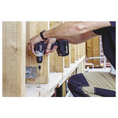 Gros plan d'un ouvrier utilisant une perceuse sans fil pour enfoncer une vis dans un cadre en bois pendant la construction.