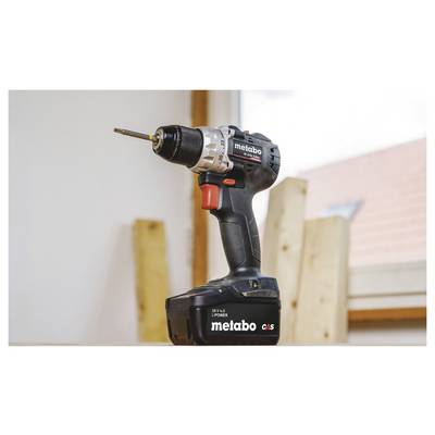 Perceuse-visseuse sans fil Metabo debout en position verticale avec un foret attaché, présentée dans un environnement de type atelier.