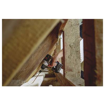 Une personne utilisant une perceuse sans fil pour fixer des poutres en bois dans un projet de construction ou de réparation, vue de dessous dans un espace de cadrage étroit.