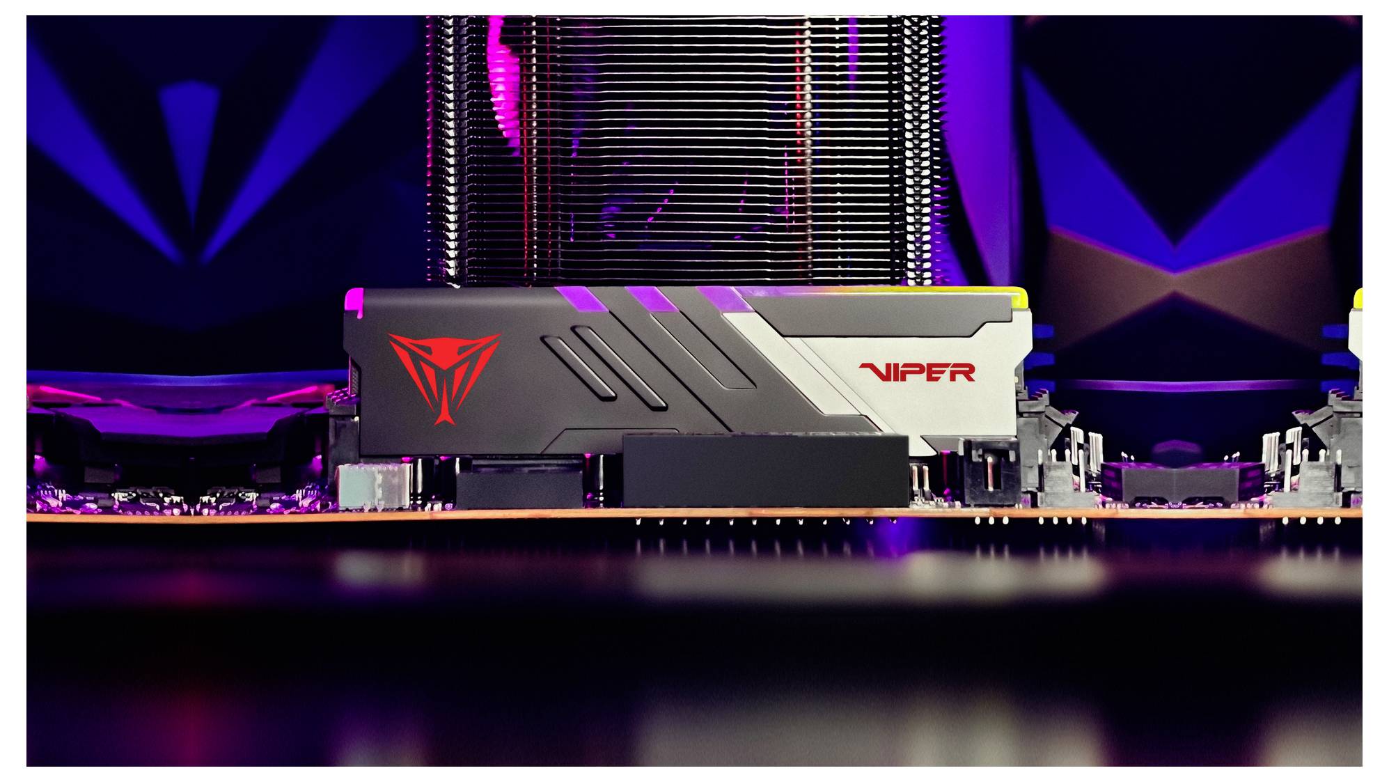 Un gros plan d'une carte mère d'ordinateur présentant un module RAM Viper au design élégant et au logo rouge, se détachant sur un fond sombre aux thèmes technologiques.