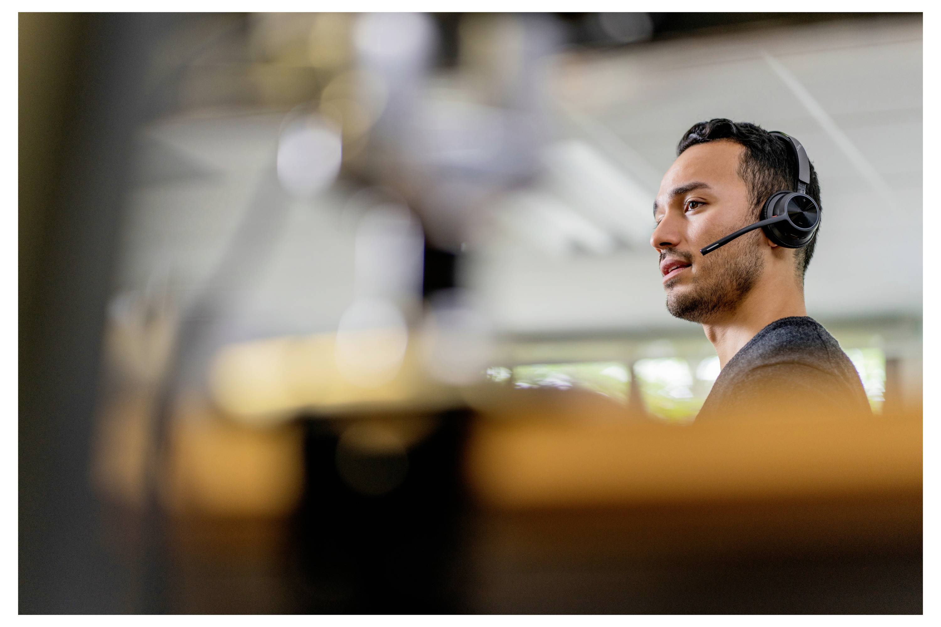 Une personne portant un casque, engagée dans une conversation, avec un arrière-plan flou d'un cadre intérieur.