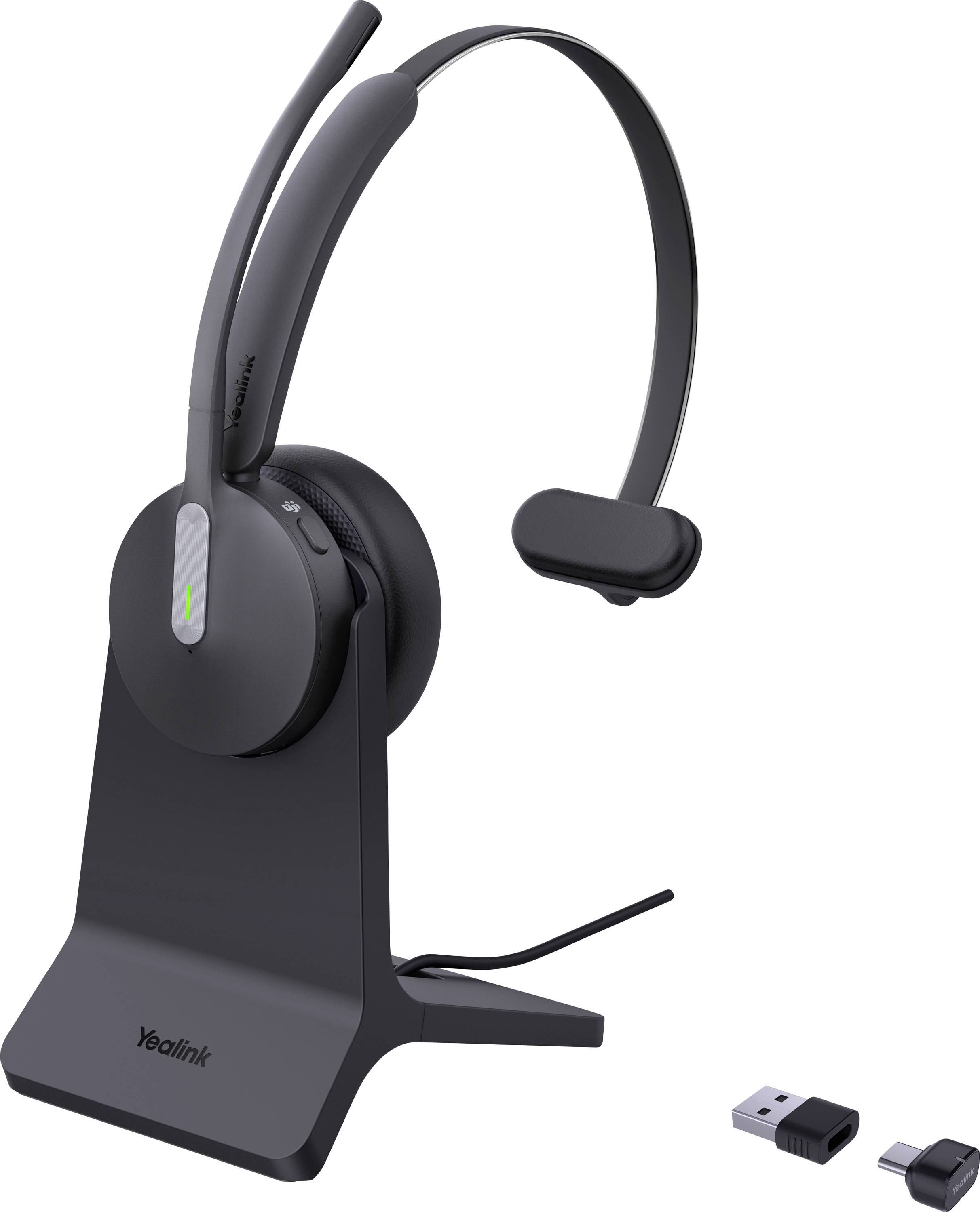 Un casque sans fil noir avec microphone sur un support, montrant un dongle USB et un adaptateur à proximité.