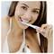 Une personne souriante utilisant une brosse à dents électrique.