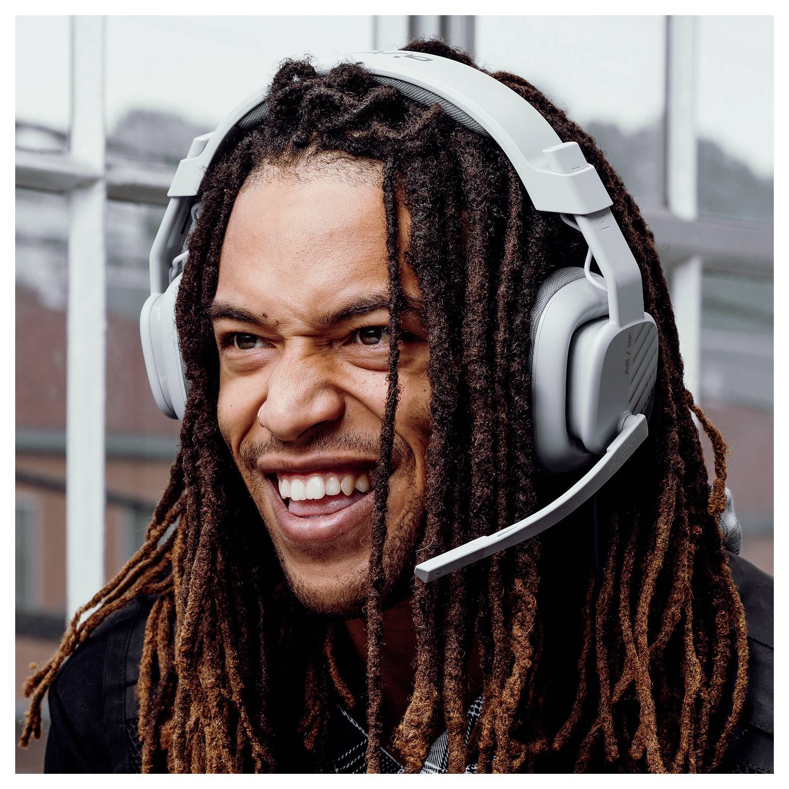 Gros plan d'un homme souriant aux dreadlocks longs portant un casque de jeu avec microphone.