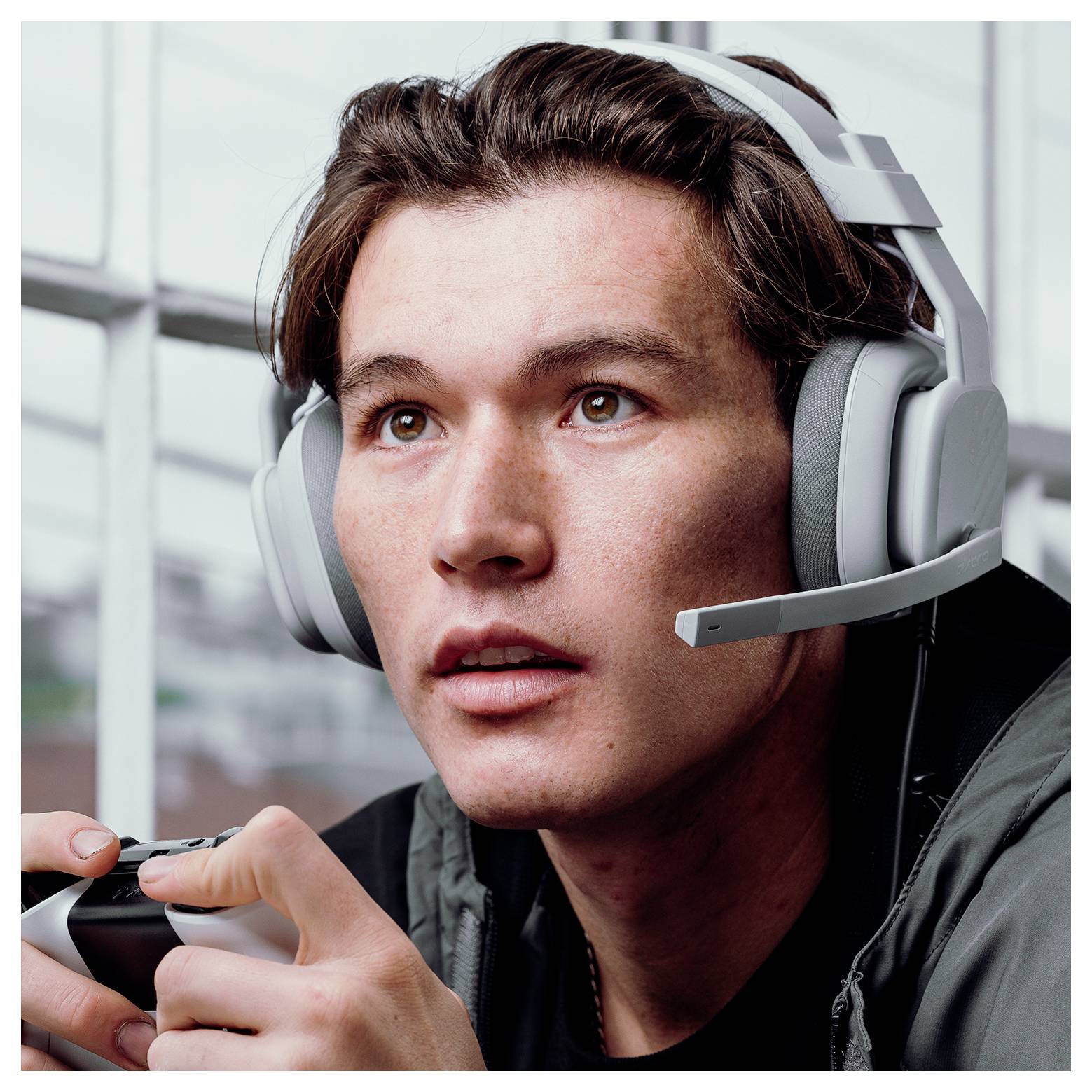 Jeune homme portant un casque de jeu qui se concentre tout en tenant une manette, probablement en train de jouer à un jeu vidéo.
