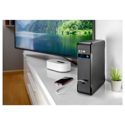 Alimentation sans interruption Black Eaton sur un meuble TV à côté d'un smartphone, d'un appareil multimédia et d'une petite plante