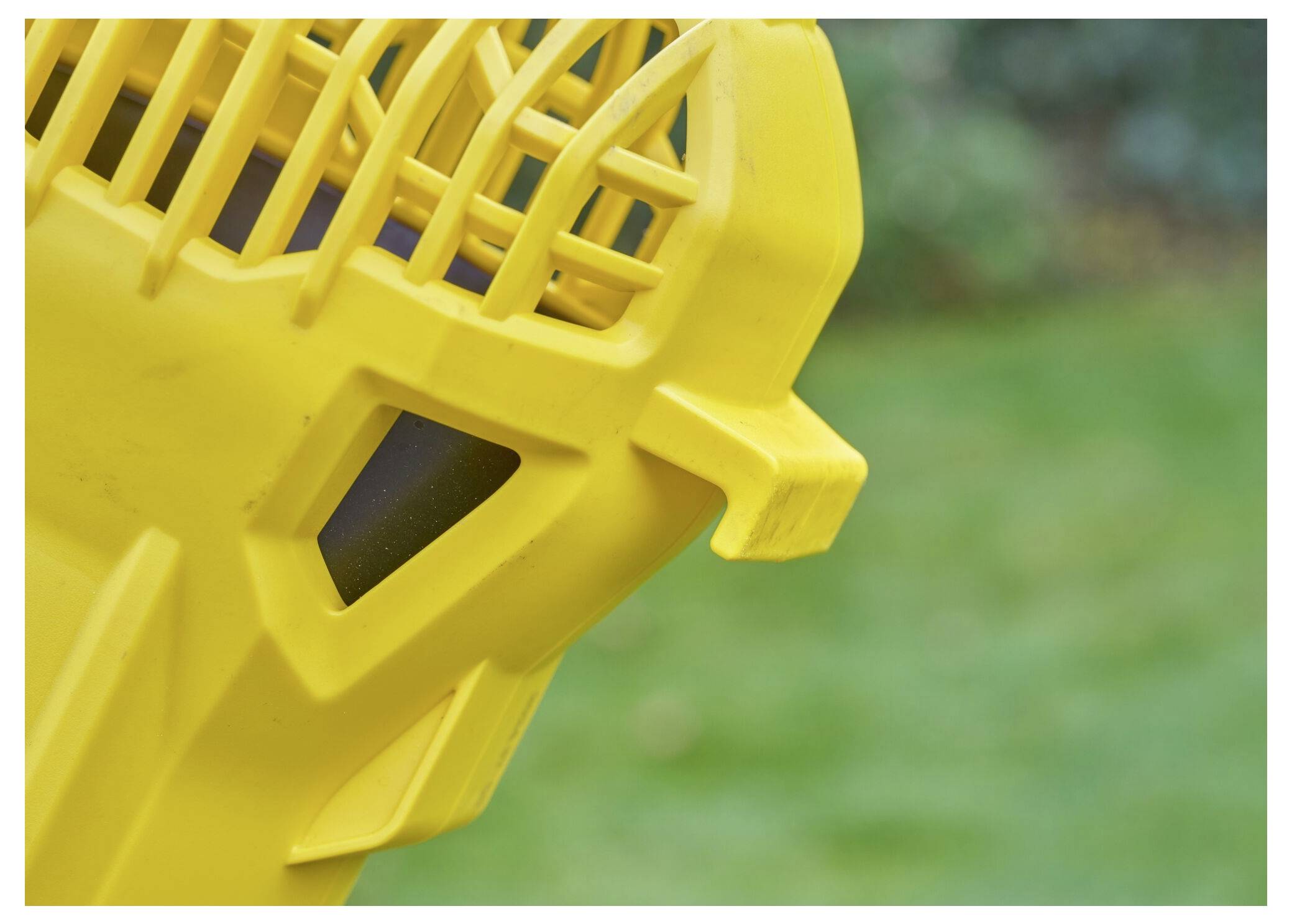 Gros plan d'un dispositif en plastique jaune avec des structures ressemblant à des évents, sur un fond vert flou.