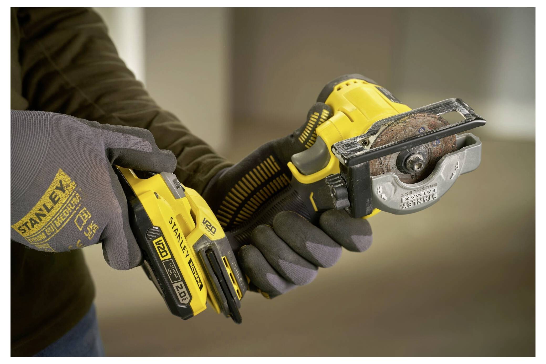 Une personne utilise un outil électrique sans fil jaune et noir pour couper du matériau, portant des gants de protection pour la sécurité.