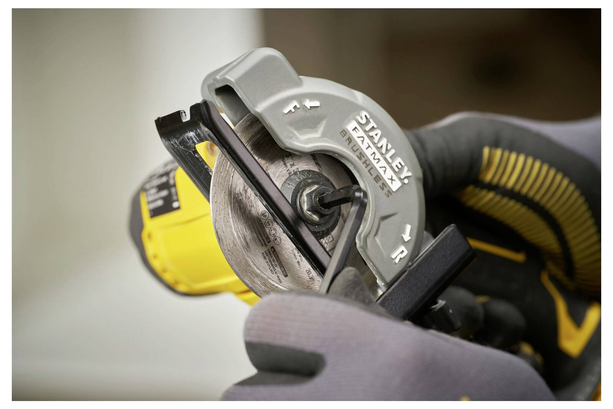 Un gros plan des mains portant des gants tenant un outil Stanley FatMax, indiquant l'alignement de la lame de l'outil pour une coupe de précision.