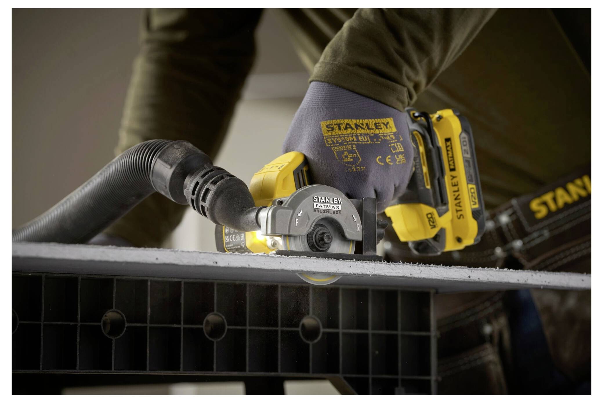 Une personne portant des gants utilise un outil électrique Stanley pour couper une planche, avec un focus sur l'outil et son utilisation pour une coupe de précision.