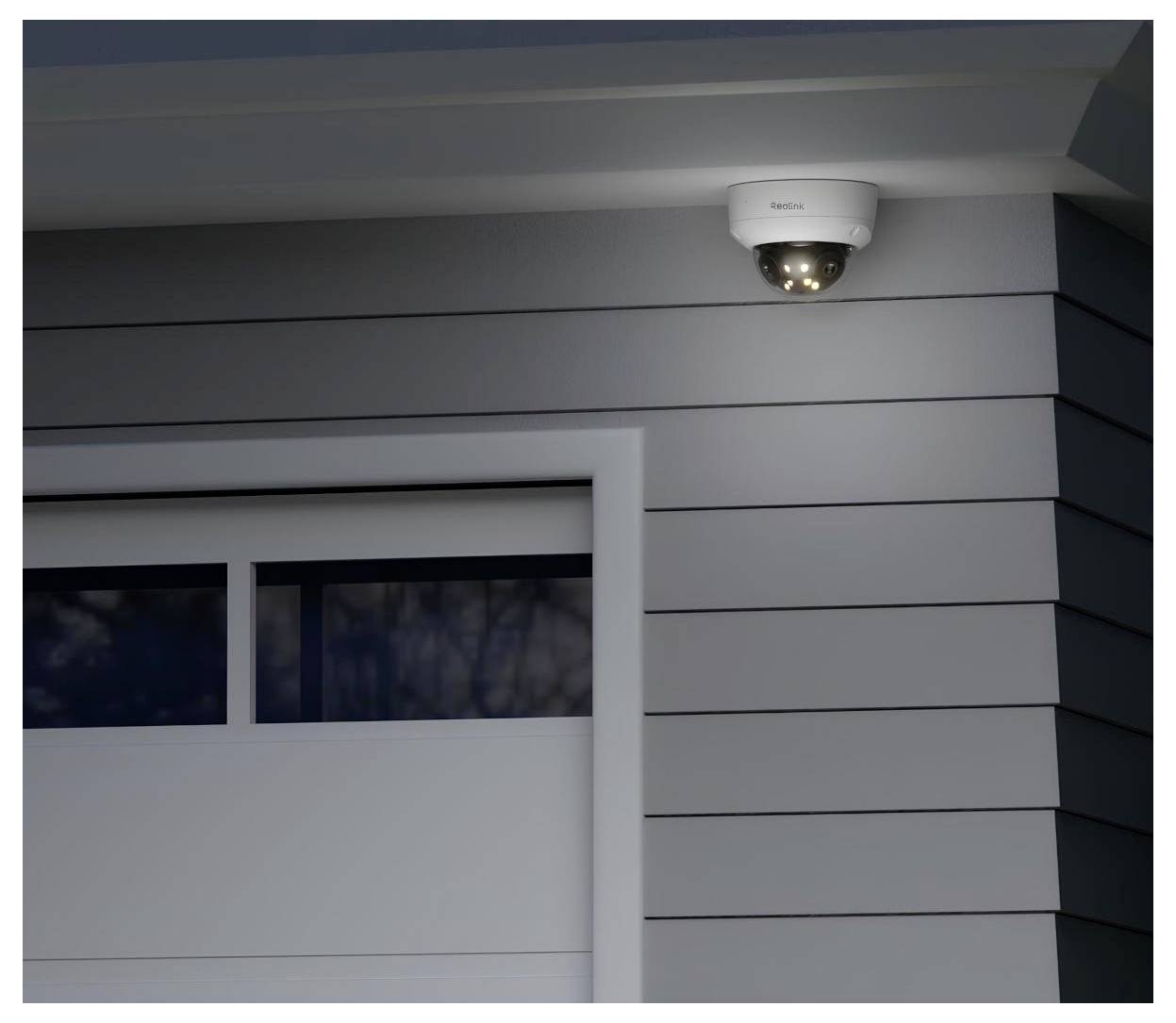 Caméra de sécurité montée sur le mur extérieur d'un bâtiment, avec des voyants LED visibles indiquant qu'elle est active et en train de surveiller.