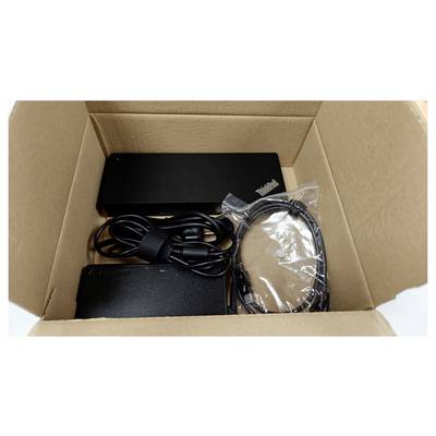 Une boîte en carton contenant un appareil électronique noir, un adaptateur d'alimentation et des câbles, soigneusement disposés pour l'expédition ou le déballage.