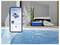 Un nettoyeur de piscine robotisé fonctionnant dans une piscine tandis qu'une main tient un téléphone intelligent affichant l'écran de l'application de contrôle du nettoyeur.
