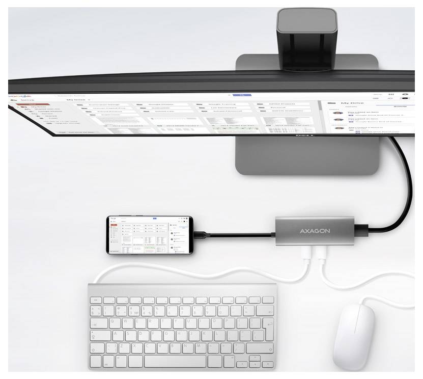 Vue de dessus d'un espace de travail comprenant un moniteur ultrawide, un téléphone, un clavier et une souris connectés via un hub d'accueil AXAGON avec des câbles.