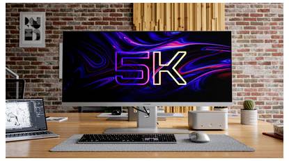 Espace de travail de bureau avec un grand moniteur ultra-large affichant « 5K » sur un fond abstrait coloré, avec un ordinateur portable, un clavier, une souris et de petits éléments de bureau.