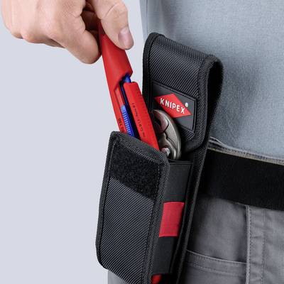 Main insérant des pinces Knipex rouges dans une pochette à outils noire sur une ceinture de travail, avec un autre outil déjà dans la poche.