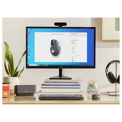 Un espace de travail de bureau avec un moniteur affichant les paramètres de la souris, un clavier et une souris sur une pile de livres, des écouteurs, une plante et une webcam.