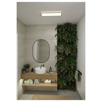 Salle de bain moderne avec vanité flottante en bois, miroir rond, lavabo vasque, serviettes, et un mur végétal intérieur vert et élancé à côté du lavabo.