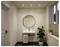 Salle de bains minimaliste moderne avec lavabo mural, miroir rond, serviette, plante en pot et fenêtre avec stores.