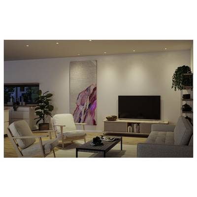 Salon moderne avec un canapé, deux fauteuils, une table basse, un meuble TV, des plantes et un grand tableau abstrait mural.