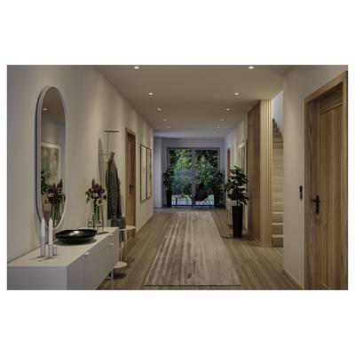 Couloir moderne avec planchers en bois, éclairage encastré, une console et un miroir sur la gauche, escaliers sur la droite, et portes vitrées s'ouvrant sur un jardin au fond.