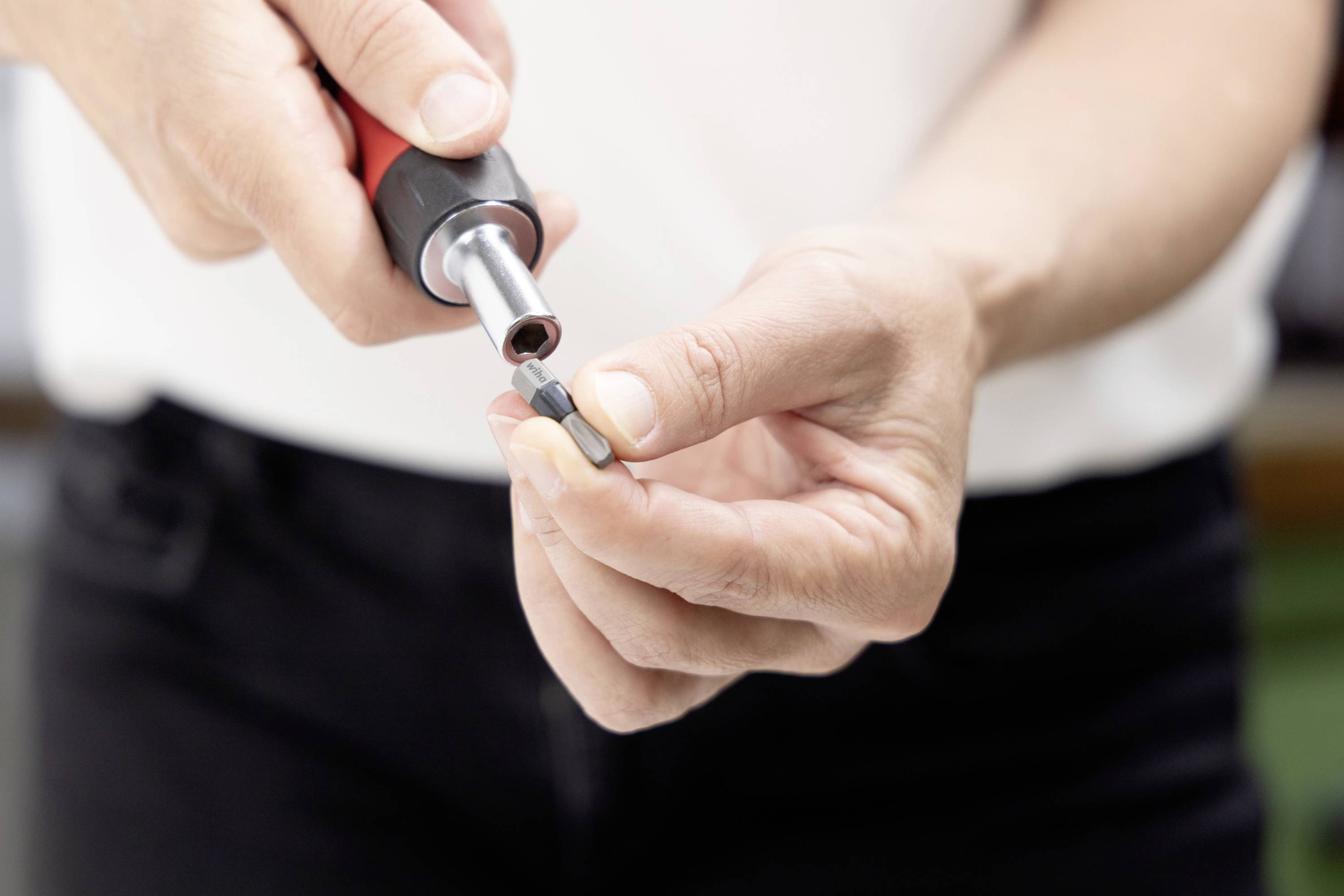 Gros plan des mains utilisant un tournevis pour serrer une petite vis ou un élément de fixation.