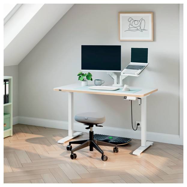 Configuration compacte de bureau à domicile avec un bureau debout, un moniteur, un ordinateur portable, un tabouret, un clavier, une plante, une tasse et un cadre d'art mural dans une pièce ensoleillée.