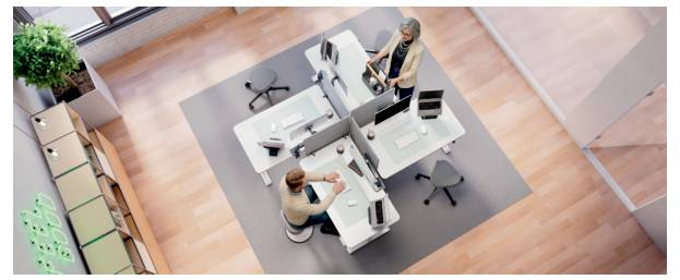Vue de dessus de deux personnes travaillant dans un bureau moderne avec des bureaux adjacents et des écrans d'ordinateur dans un espace de travail partagé.