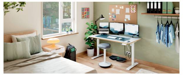 Un espace de travail de chambre à coucher bien rangé avec un bureau, trois moniteurs, un tabouret, un sac pour ordinateur portable, une plante, des notes murales et des vêtements suspendus à côté du lit.