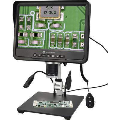 Microscope numérique affichant un circuit imprimé agrandi sur son moniteur, le circuit étant positionné sur la platine en dessous et une télécommande portative attachée.