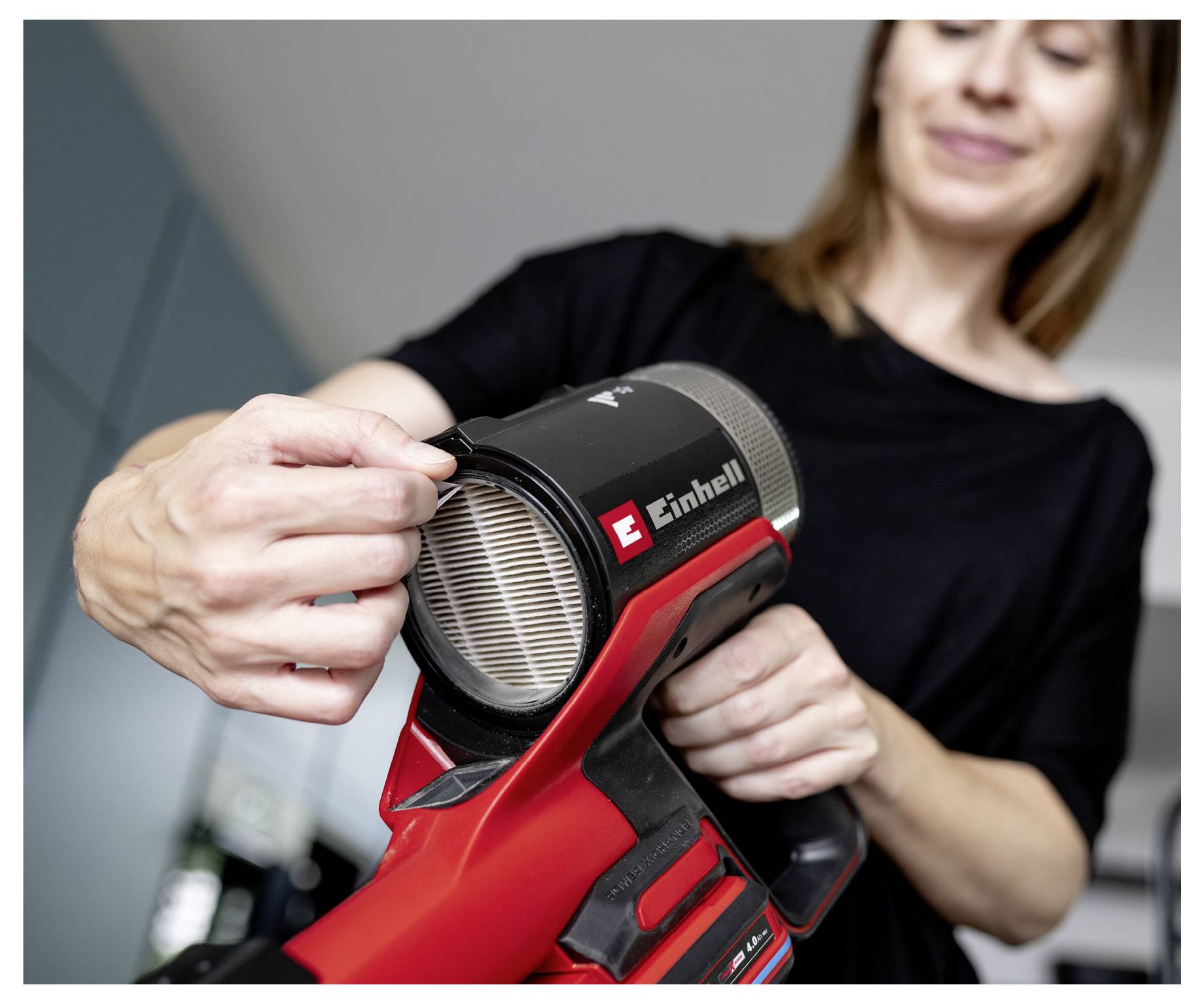 Personne retirant un filtre d'un aspirateur sans fil Einhell rouge et noir