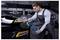 Un mécanicien qui polit le phare avant d'une voiture de sport noire dans un garage en utilisant une polisseuse portative.