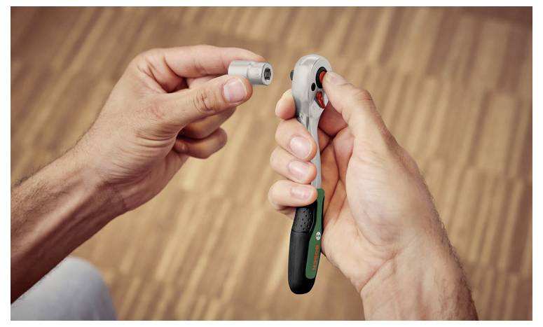 Des mains utilisant une clé à cliquet et une douille, montrant un outil en train d'être attaché pour serrer ou desserrer des pièces matérielles.