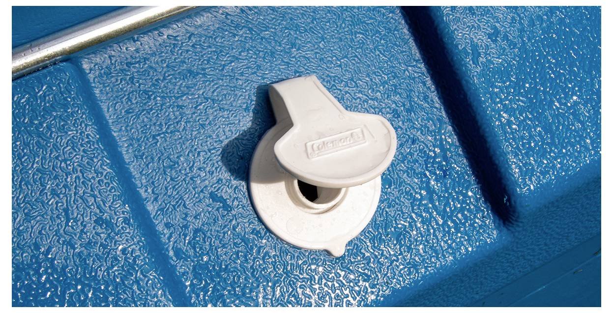 Gros plan d'un loquet en plastique blanc ou d'un bouchon de vidange monté sur une surface bleue texturée.
