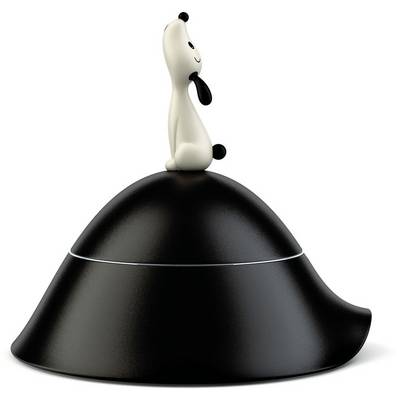 Un petit chien jouet blanc et noir assis sur le dessus d'un objet en forme de cloche noire sur un fond blanc.